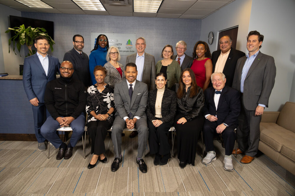 Group of people standing and sitting in front of desk